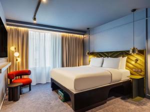a hotel room with a bed and a red chair at TRIBE Krakow Old Town in Krakow +149 photos
