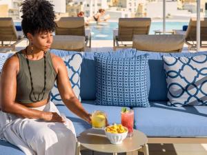 a woman sitting on a couch with a bowl of fruit at Novotel Malta Sliema in Il-Gżira