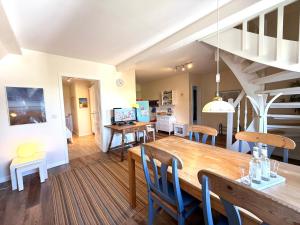 a dining room and living room with a table and chairs at Deichhof Whg 27 in Dunsum