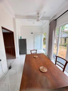 a wooden table in a living room with a kitchen at Blue Wave Holiday Villa in Weligama