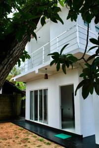 a white house with a balcony on top of it at Blue Wave Holiday Villa in Weligama