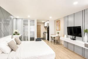 a white bedroom with a large bed and a flat screen tv at Sweet room in Nimnan in Chiang Mai