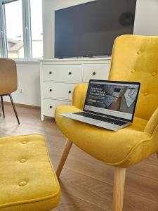 a laptop computer sitting on a yellow chair at Apartmán KVETINKA v centre Žiliny s KAVIARŇOU in Žilina