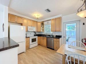 a kitchen with wooden cabinets and a white refrigerator at Blue Wave Villa East in Anna Maria +58 photos
