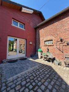a red brick building with a door and a patio at Comme à la Ferme in Durbuy