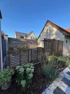 a garden with a wooden fence and some plants at Gîte du Cap Romain in Bernières-sur-Mer