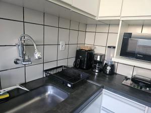 a kitchen counter with a sink and a microwave at Apto Completo com Conforto e Garagem Proximo a USP e HC in Ribeirão Preto