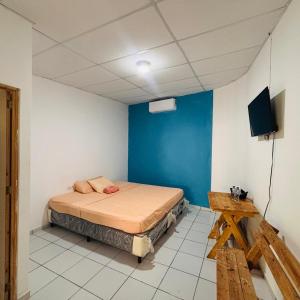 a bedroom with a bed and a blue wall at LA CASONA SV Hostal in La Libertad