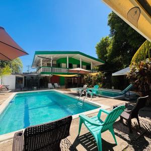 a swimming pool with chairs and a house at LA CASONA SV Hostal in La Libertad