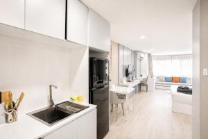 a kitchen with white cabinets and a black refrigerator at Sweet room in Nimnan in Chiang Mai