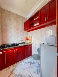 a kitchen with red cabinets and a white refrigerator at Bisso Hotel Bonaberi in Douala