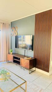 a living room with a television and a table at Waterfall Apartments Waterfall Cres in Midrand