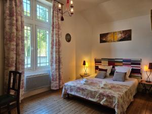 a bedroom with a bed and two windows at Aux grilles du Château de Saint-Aignan, à 2km de Beauval, les maisons de Sidonie et Léonard in Saint-Aignan