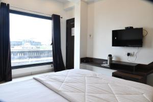 a bedroom with a bed and a large window at Hotel Shreeji Palace in Ābu Road