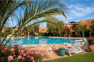 a swimming pool with two chairs and a palm tree at atlas golf resort in Marrakesh