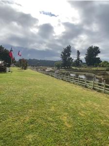 a grassy field with a fence and a river at Cabañas El Rincon del Sur in Colaco