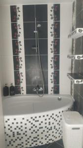 a bath tub in a bathroom with a black and white tile wall at Apartamenty Trzcińsko 47 in Janowice Wielkie