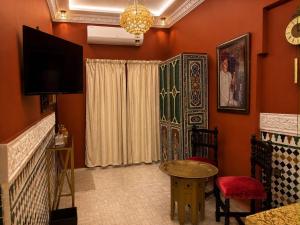 a living room with a television and a table and chairs at Dar Laabi - Riad Aya in Fez
