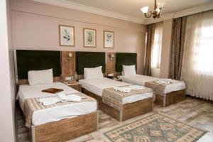 a hotel room with two beds and two tables at Alkış Otel in Iğdır
