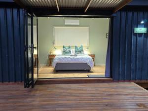 a bedroom with a bed with blue pillows at Moss & Moon Cabins in Stormsrivier