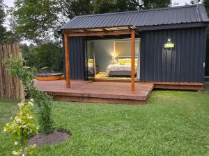 a black shed with a bed on a deck at Moss & Moon Cabins in Stormsrivier