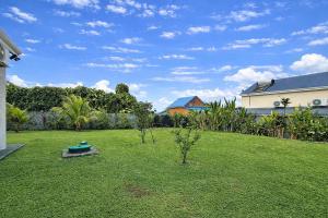 a yard with a green lawn with trees and a house at Private Villa, Castel in Lamentin