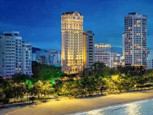 a city at night with palm trees and buildings at Mercure Nha Trang Beach in Nha Trang