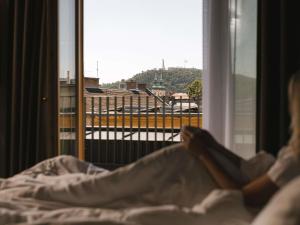 a woman laying in bed looking out of a window at You Hotel Budapest - Handwritten Collection in Budapest +166 photos