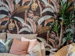 a couch with pillows in front of a wall with plants at The Sebel Byron Bay in Byron Bay