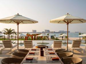 a table with chairs and umbrellas on a patio at SO Ras Al Khaimah Hotel & Resort-Ultra All Inclusive in Ras al Khaimah