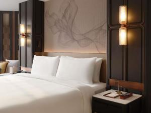 a bedroom with a large white bed and a table at Fairmont Bangkok Sukhumvit in Bangkok