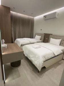 a hotel room with two beds and a desk at The Pearl Inn in Nizwa