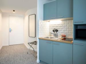 a small kitchen with blue cabinets and a sink at Adagio Access Paris Nanterre in Nanterre
