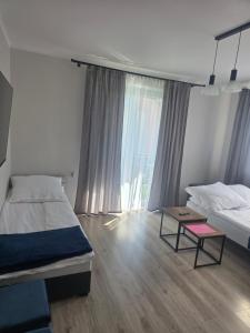 a bedroom with two beds and a table and a window at Apartament Stokrotka in Olszyny