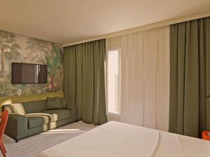 a hotel room with a bed and a couch at Ibis Styles Vannes Pte Golfe in Vannes +116 photos