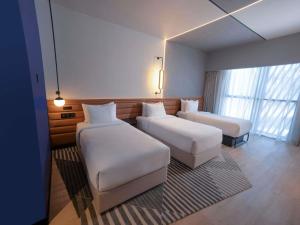a hotel room with two beds and a couch at Novotel Madinah in Medina