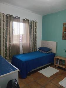 a bedroom with a blue bed and a window at KaDinizHouse in Caraguatatuba