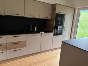 a kitchen with white cabinets and a black counter top at Alpenoase Ennstal in Ennsling +4 photos