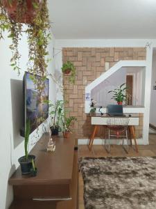 a living room with a tv and a table with plants at KaDinizHouse in Caraguatatuba