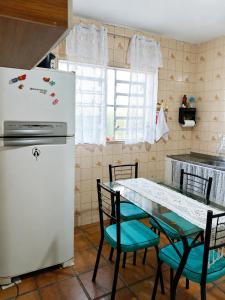 a kitchen with a table and a white refrigerator at KaDinizHouse in Caraguatatuba