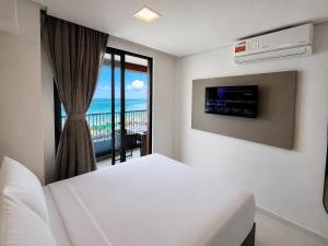 a white bedroom with a bed and a balcony at Smeralda del Mare by AFT in Porto De Galinhas