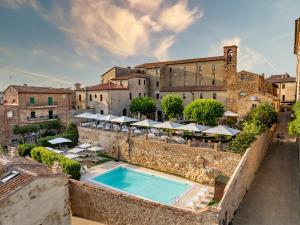 an outdoor swimming pool with tables and umbrellas on a building at Relais Cloister Pienza in Pienza