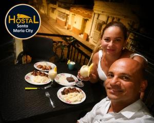 a man and a woman sitting at a table with food at Hostal Santa Maria City in Santa Marta