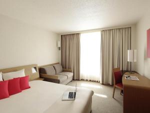 a hotel room with a large bed and a couch at Novotel Metz Centre in Metz