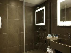 a bathroom with a shower and a sink and a mirror at Novotel Metz Centre in Metz