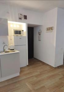 a white kitchen with a sink and a microwave at Brasov Sfat Apartament in Braşov +2 photos