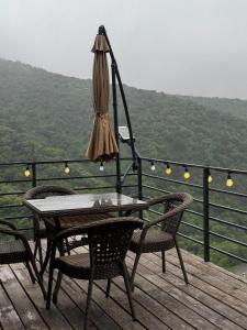 a table and chairs on a deck with an umbrella at SkyCamp Almaty in Almaty +4 photos