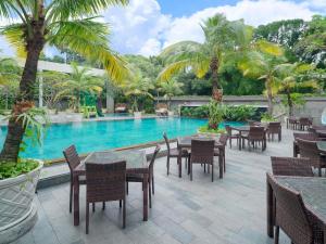 a resort with a swimming pool with tables and chairs at Novotel Solo in Solo