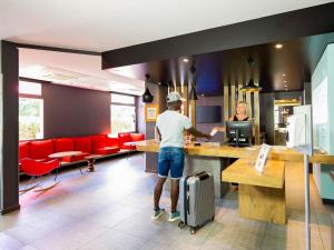 a person standing at a counter in a restaurant at ibis Mulhouse Ile Napoleon in Sausheim +33 photos