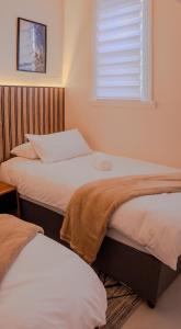 two twin beds in a room with a window at Sand In My Shoes in Muizenberg